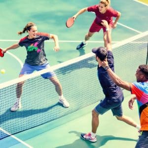 Players at the net in an intense pickleball match.