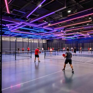 Indoor pickleball court with players and vibrant lighting.